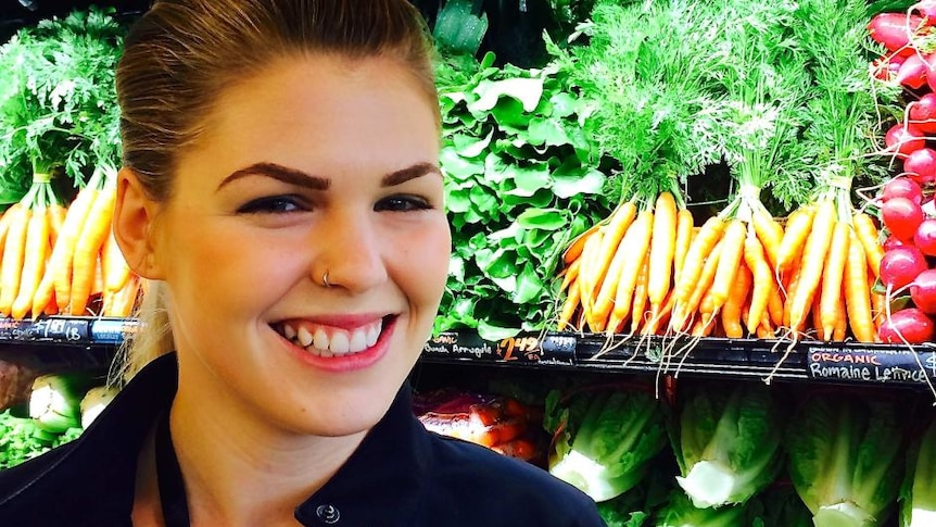 Belle Gibson smiles in front of organic fruit and vegetables, in a story about fake online personas.