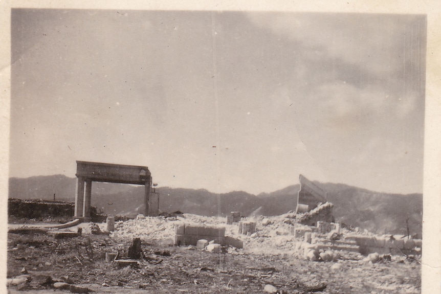 Remnants of building and lots of rubble, hills in background black and white photo