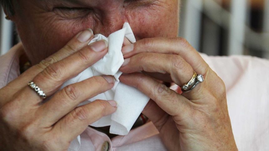 A woman blows her nose.