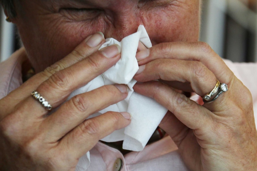 an elderly woman blowing her nose