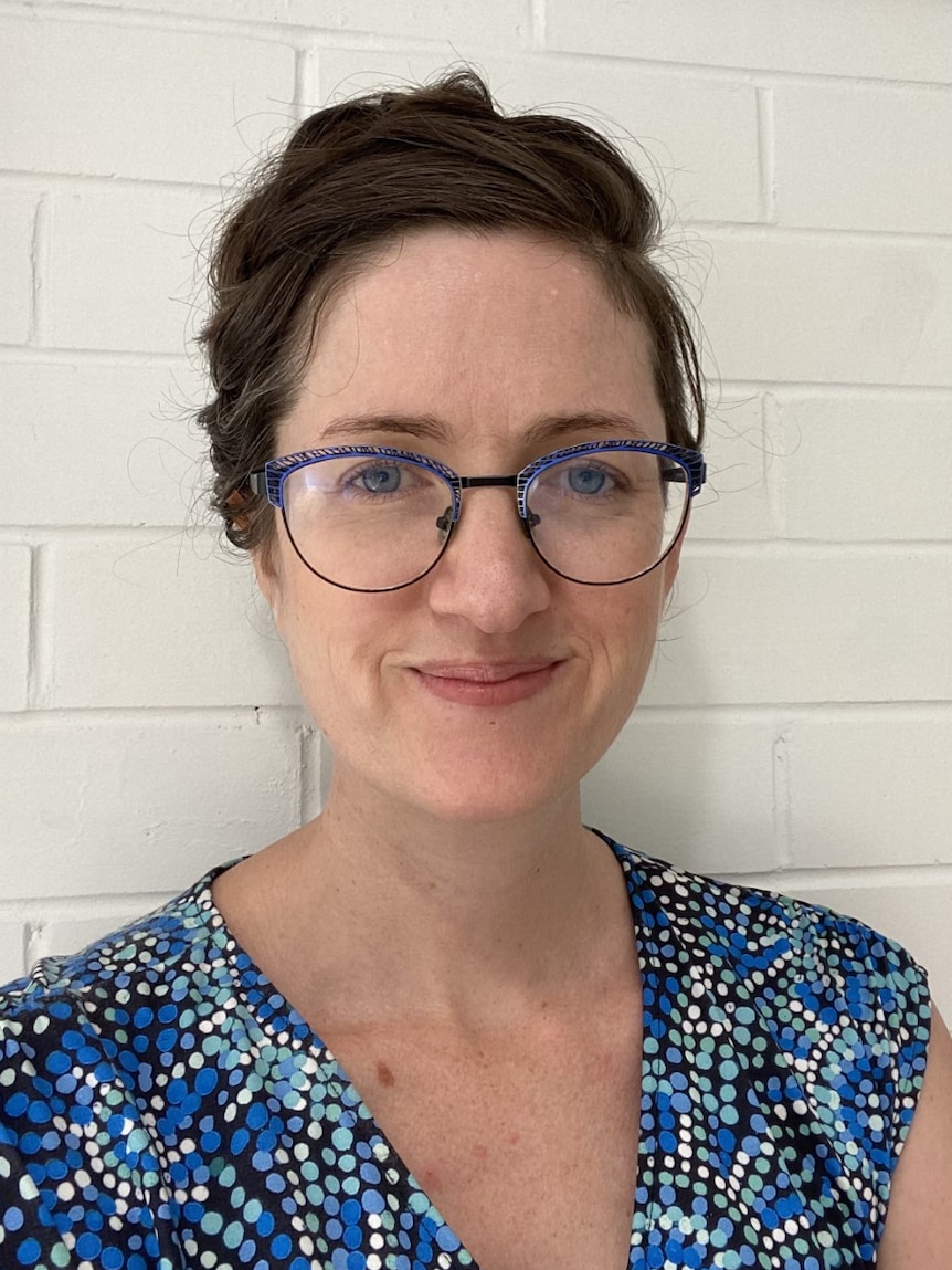 Gillian O'Brien wears blue thin-framed glasses and a polka dot shirt in a headshot.