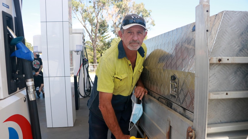 A man filling his ute with petrol from a bowser.