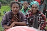 Two women sit in a field in Papua New Guinea
