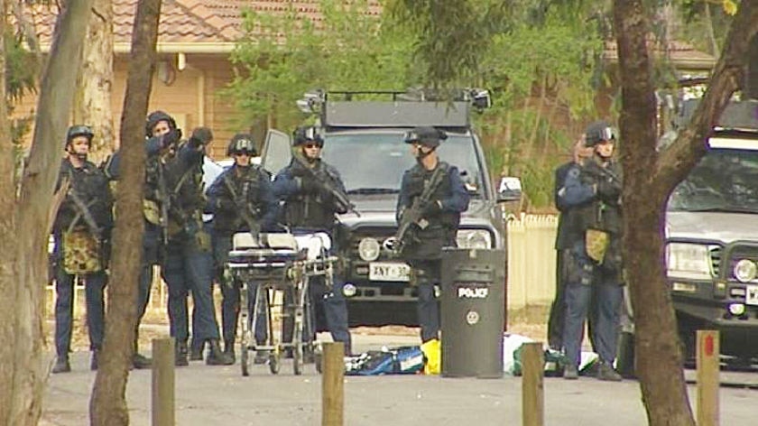Officers stand around a body at Parafield Gardens after police shot a man dead