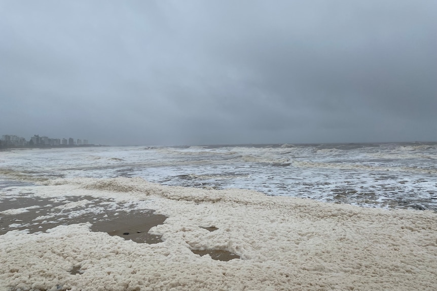 A beach covered in foam. 