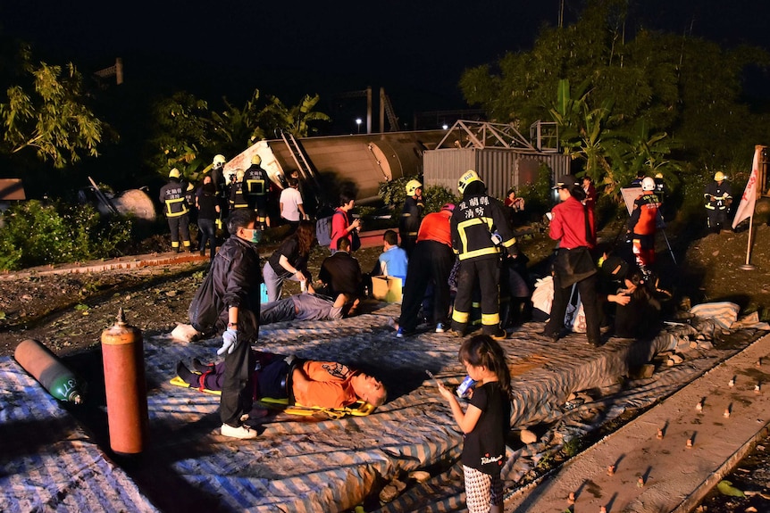 Rescue workers tend to the injured at the site of a train derailment in Taiwan. One person is visible on a stretcher.