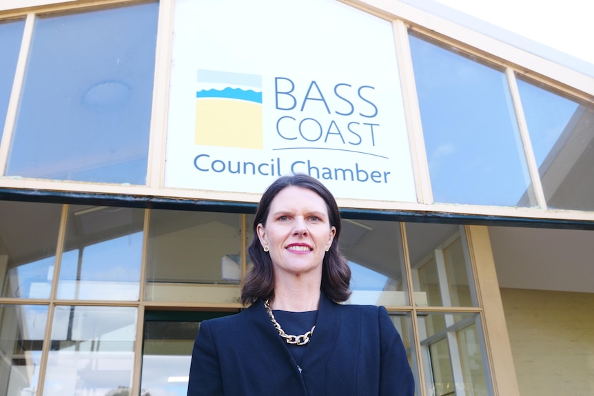 A woman in a suit standing in front of a council building