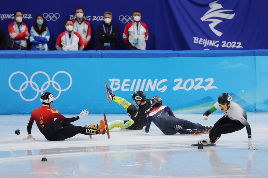 Quatre hommes sont assis sur la glace en patins aux Jeux olympiques