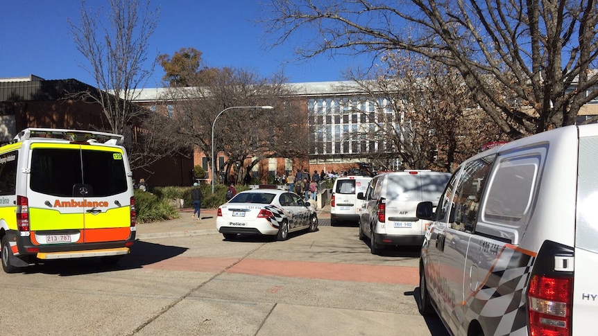 Police cars and an ambulance parked out the front of a building