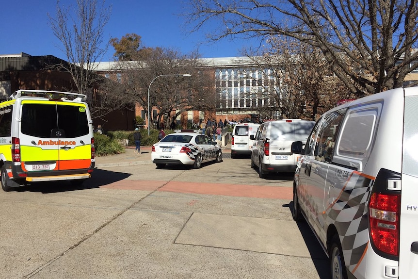 Police cars and an ambulance parked out the front of a building