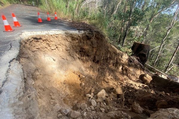 A large landslip below a road, with part of the road fallen away.