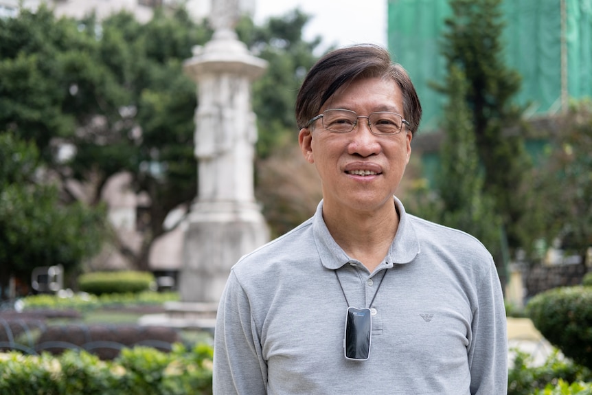 A Chinese man wearing glasses smiles. 