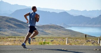 Man running on road with lake and mountains behind