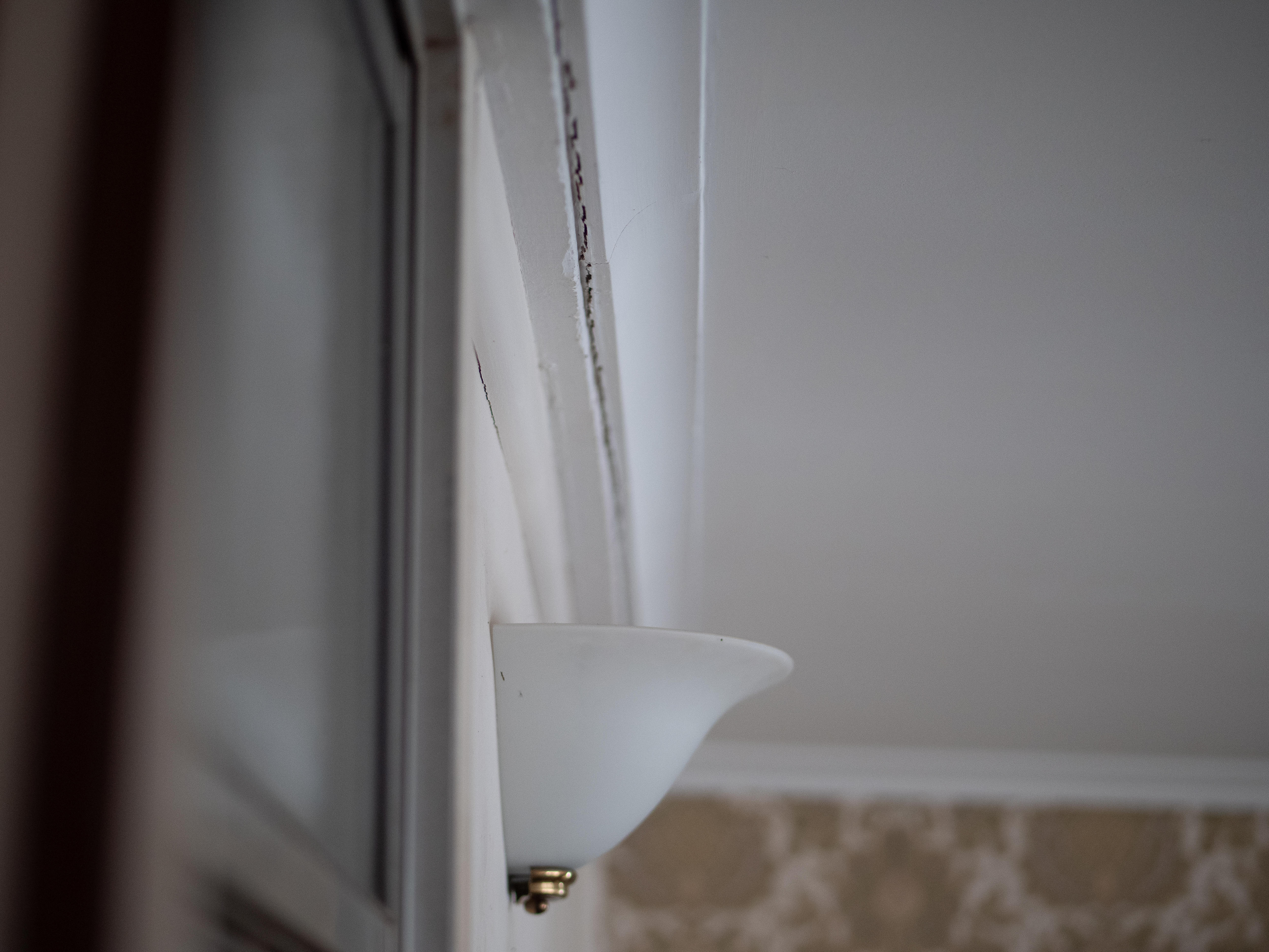 La pintura blanca se está descascarando entre la pared y el techo.