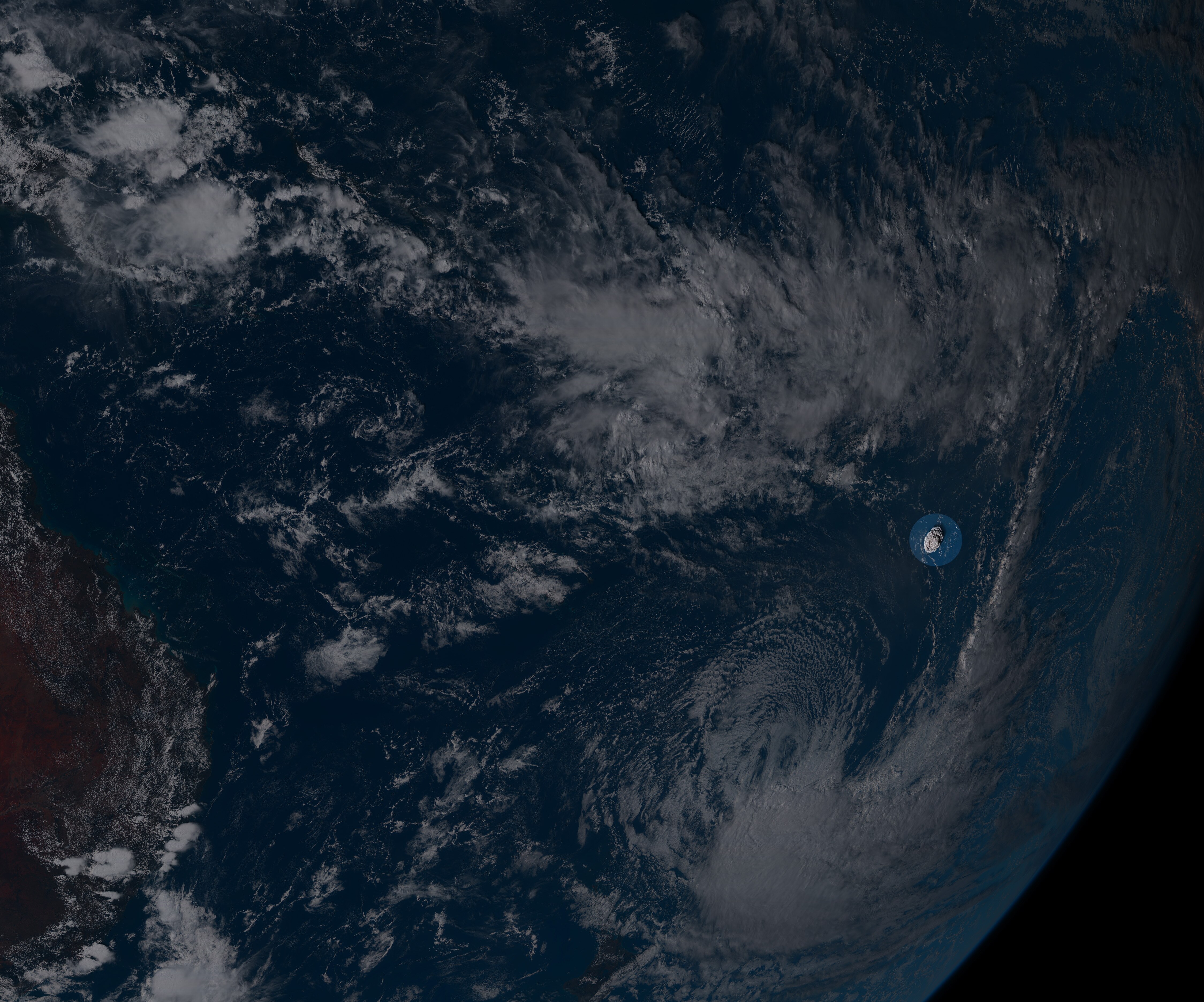 An expanding cloud of smoke is seen highlighted in the ocean. The image is taken from space.