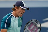 Alex de Minaur shouts and clutches his tennis racquet at the US Open.