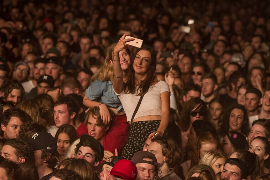 Girls take a selfie in a music crowd