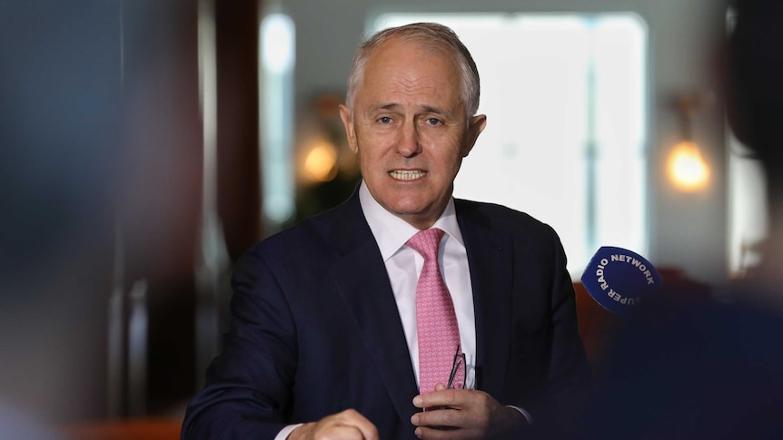 Malcolm Turnbull speaks to the media, holding his glasses in one hand and clenching his other first.