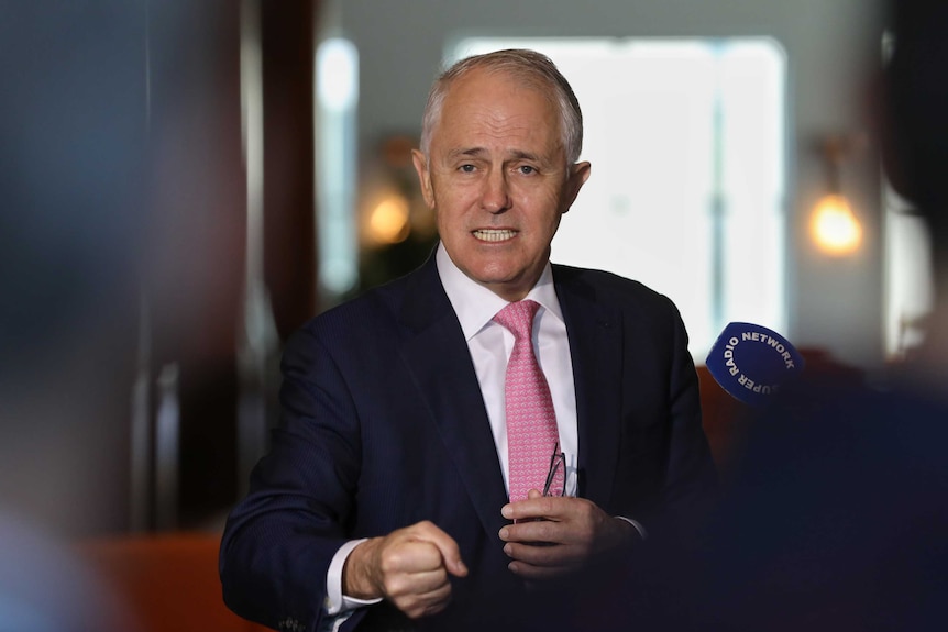 Malcolm Turnbull speaks to the media, holding his glasses in one hand and clenching his other first.