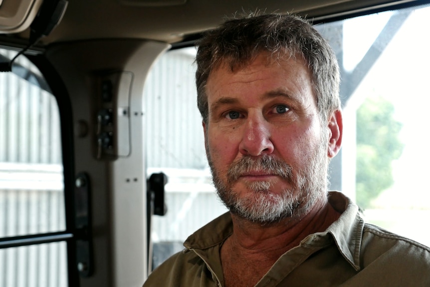 a man sitting in a tractor looks at the camera with a serious expression