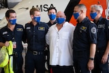 Man embraces AMSA officers in front of plane