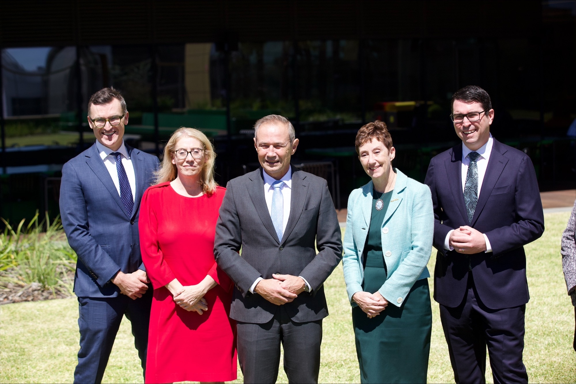 Cinco pessoas lado a lado tirando uma foto com as mãos entrelaçadas 