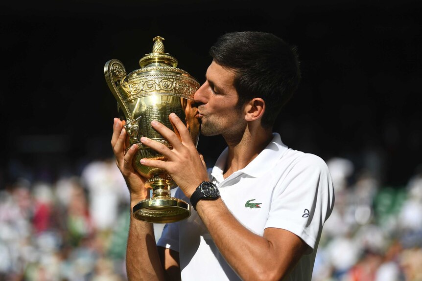 Novak Djokovic kisses the Wimbledon trophy on Centre Court in July 2018.