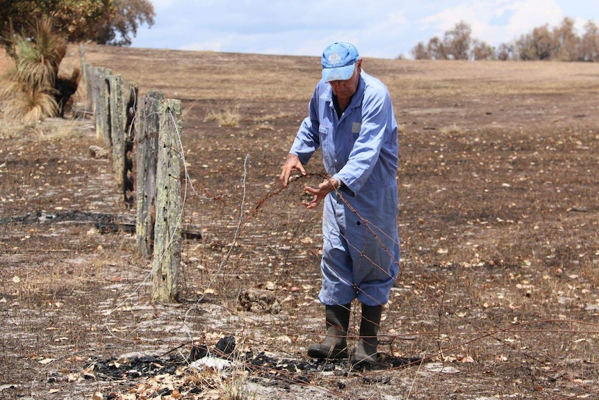 Alfred Bonbara examines a section of fire-damaged fence.