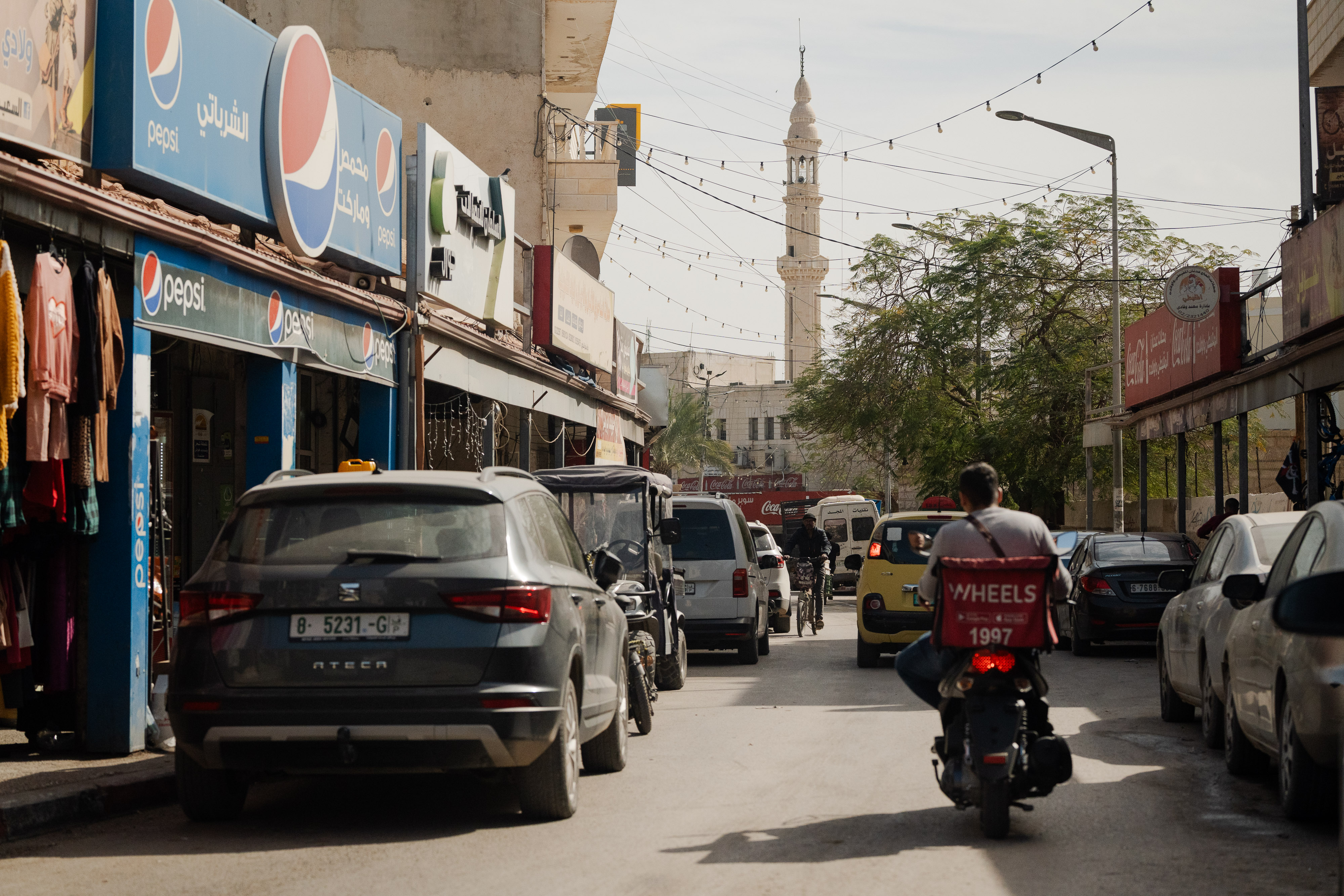 A person on a motorbike drives along a road near billboards.