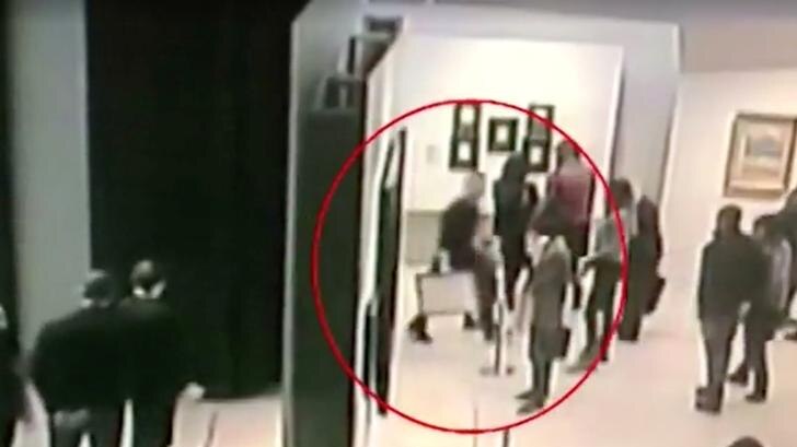 Security footage screen shot shows Russian art thief walks through crowded gallery with painting