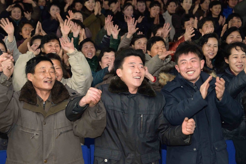 North Korean smiling and raising their hands.
