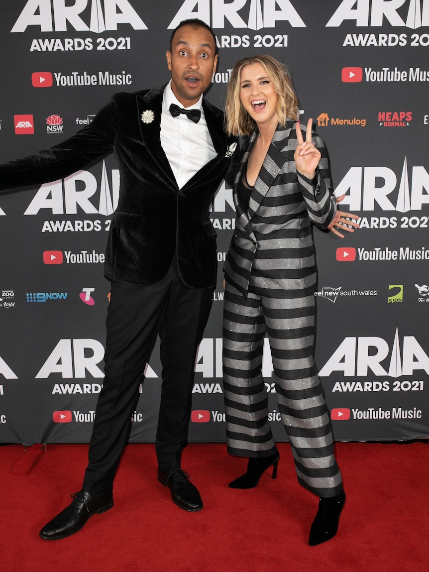 A man in a tuxedo and a woman in a stripy suit.