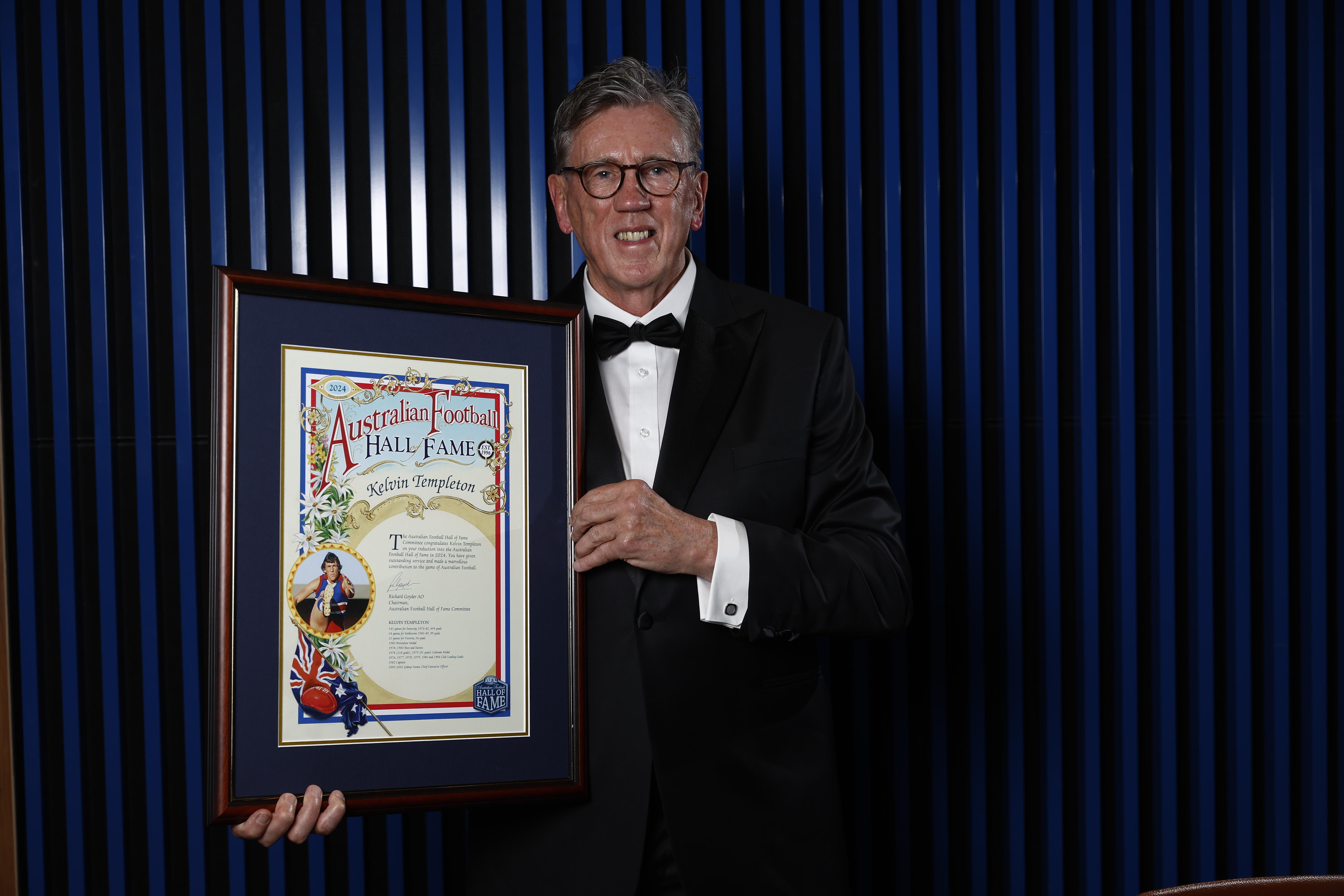 Um homem mais velho de óculos segurando um certificado decorativo emoldurado