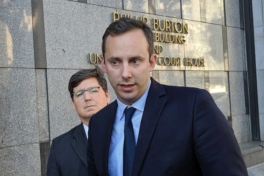 A man in a suit stands outside a courthouse in San Francisco.