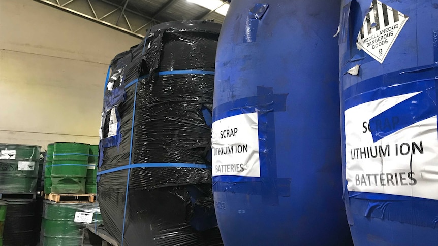 Blue plastic drums full of batteries await recycling inside a factory.