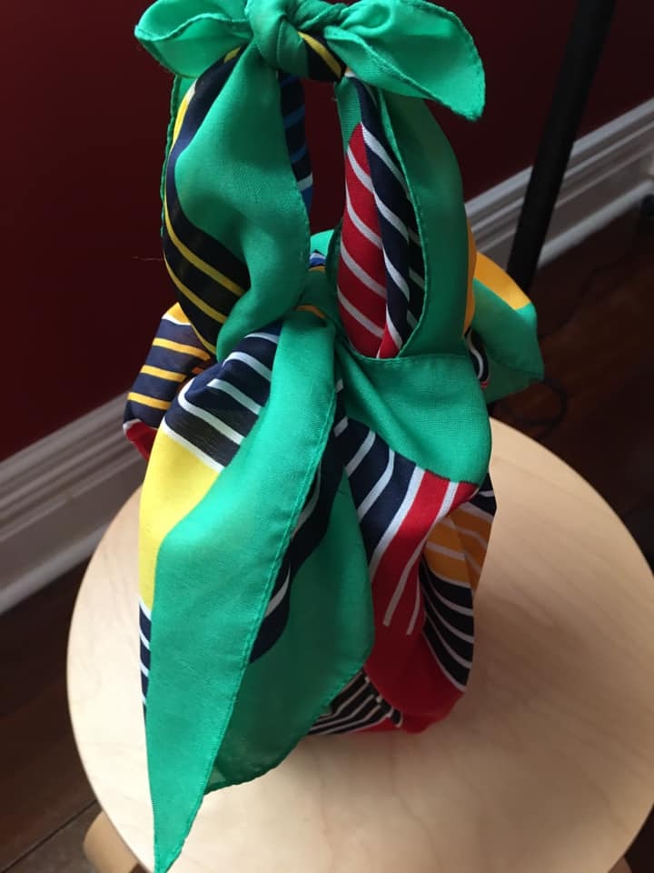 A green, navy and red scarf tied neatly around a present.