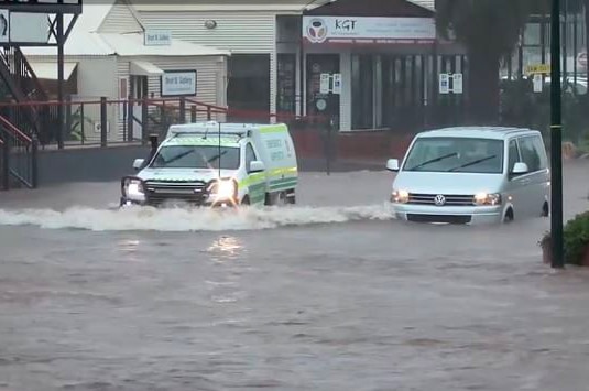 Two cars on a flooded road in the centre of Broome, with the water level approaching thetop of their tyres.