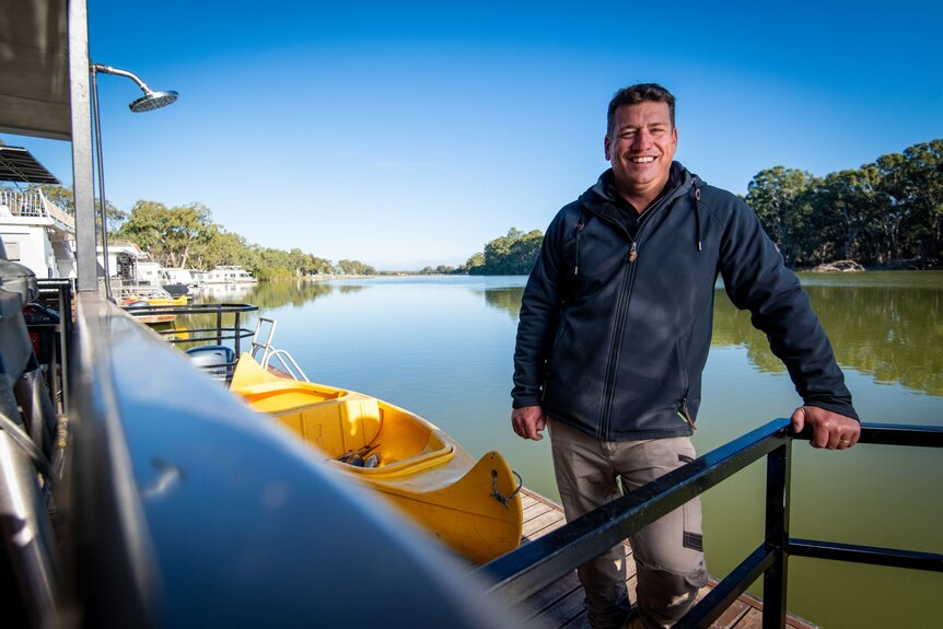 A man leans on railings along the River Murray.
