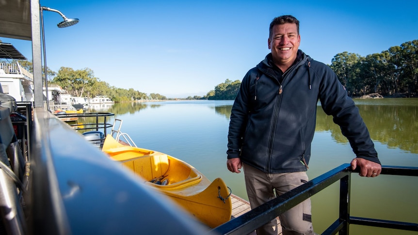 A man leans on railings along the River Murray.