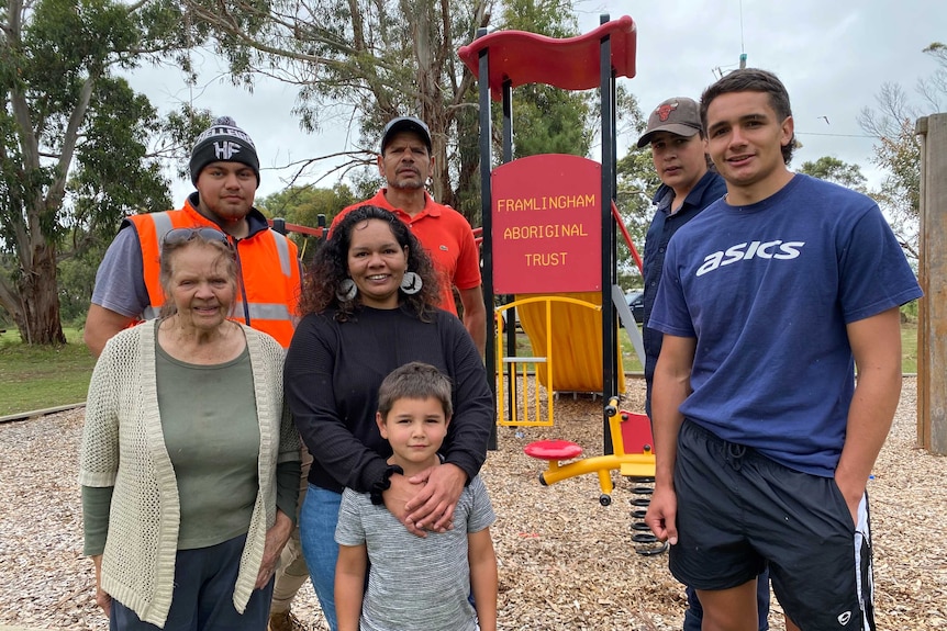 A family stands in front of a slide saying