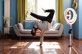 Photo of a young Asian boy break dancing in his living room in front of a camera and ring light. 