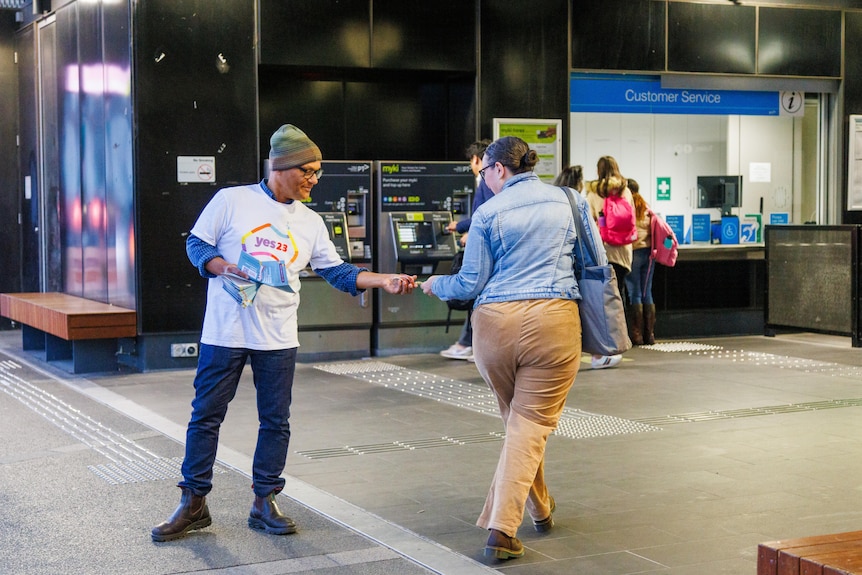 Viresh Ratnayeke hands a flyer to someone walking past him outside Bentleigh train station.