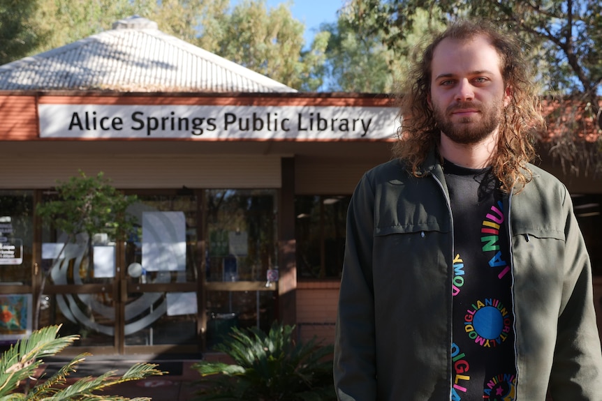 man with long, brown hair and beard standing in front of Alice Springs Public Library 