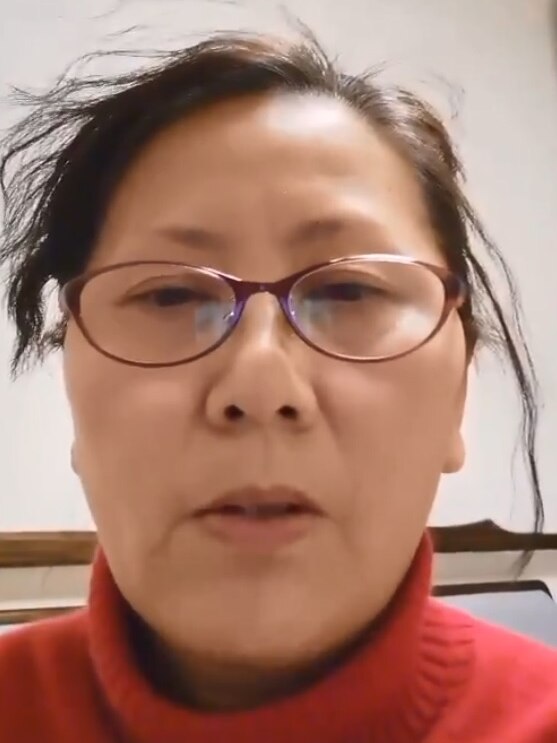 A Chinese woman wearing a red turtleneck and wearing glasses