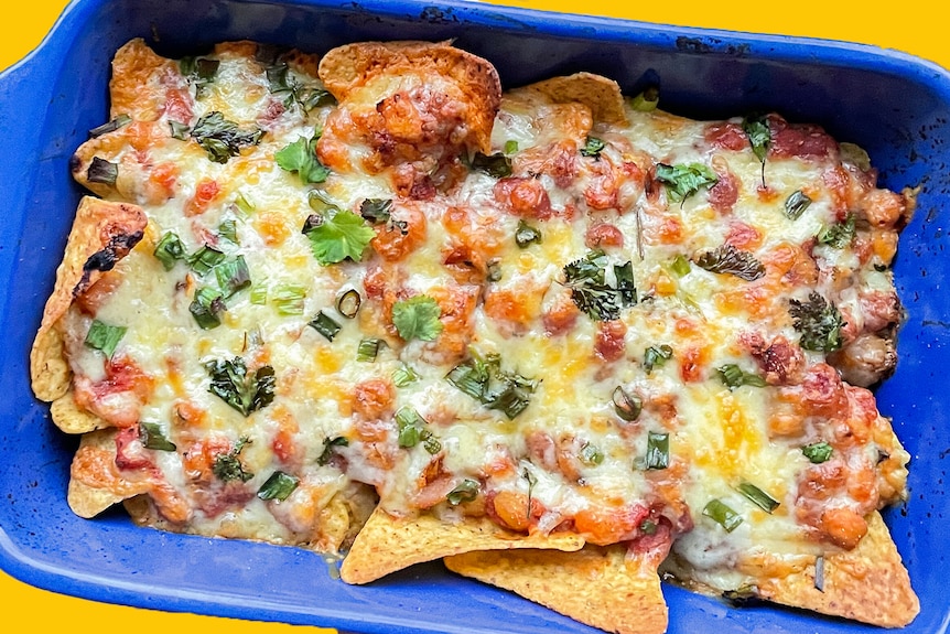 Cheesy nachos in a blue oven-safe dish.