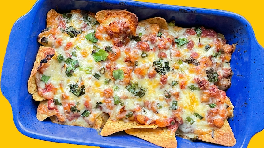 Cheesy nachos in a blue oven-safe dish.