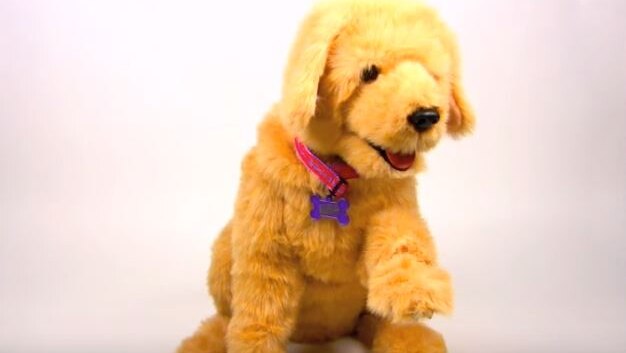 A small, yellow, fluffy pretend dog, with pink collar, open mouth and one paw raised.