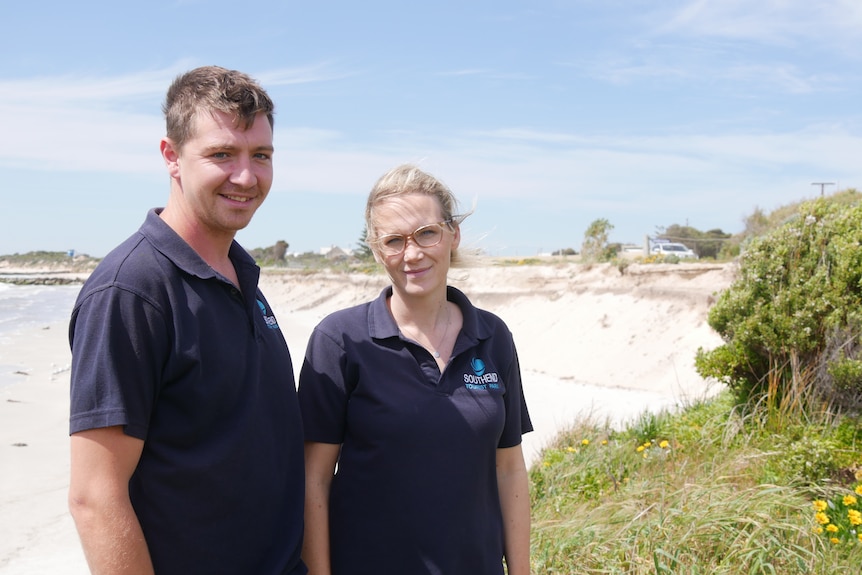 A man and woman standing next to a beach. 