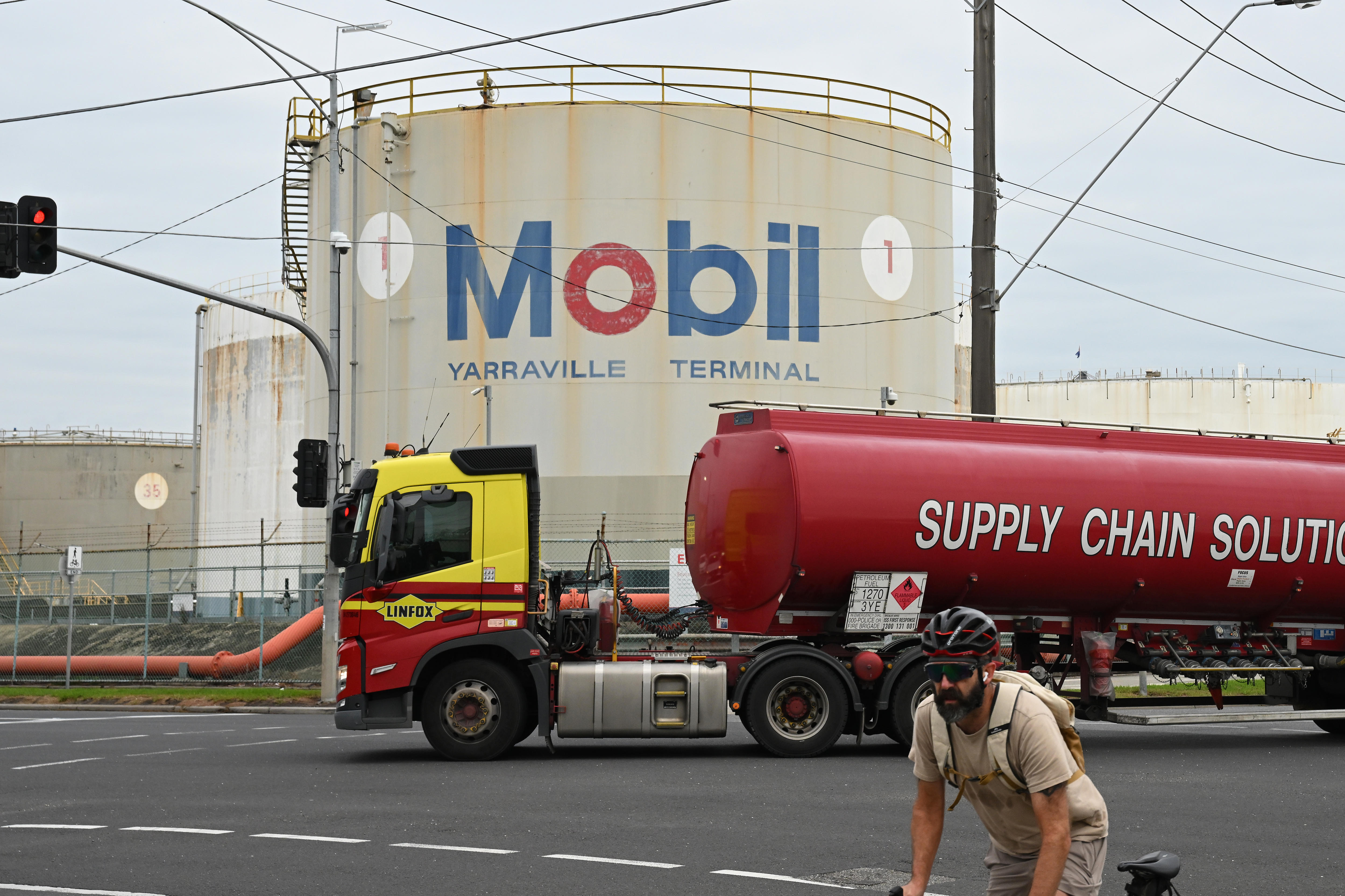 A truck transporting petroleum fuel passes by signage at the ExxonMobil Yarraville Terminal