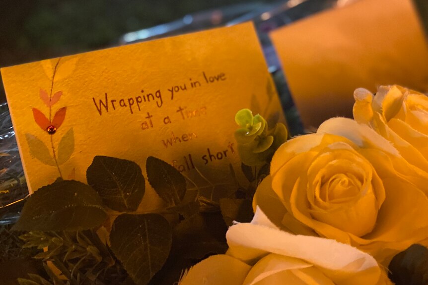 A tribute with roses and a note.